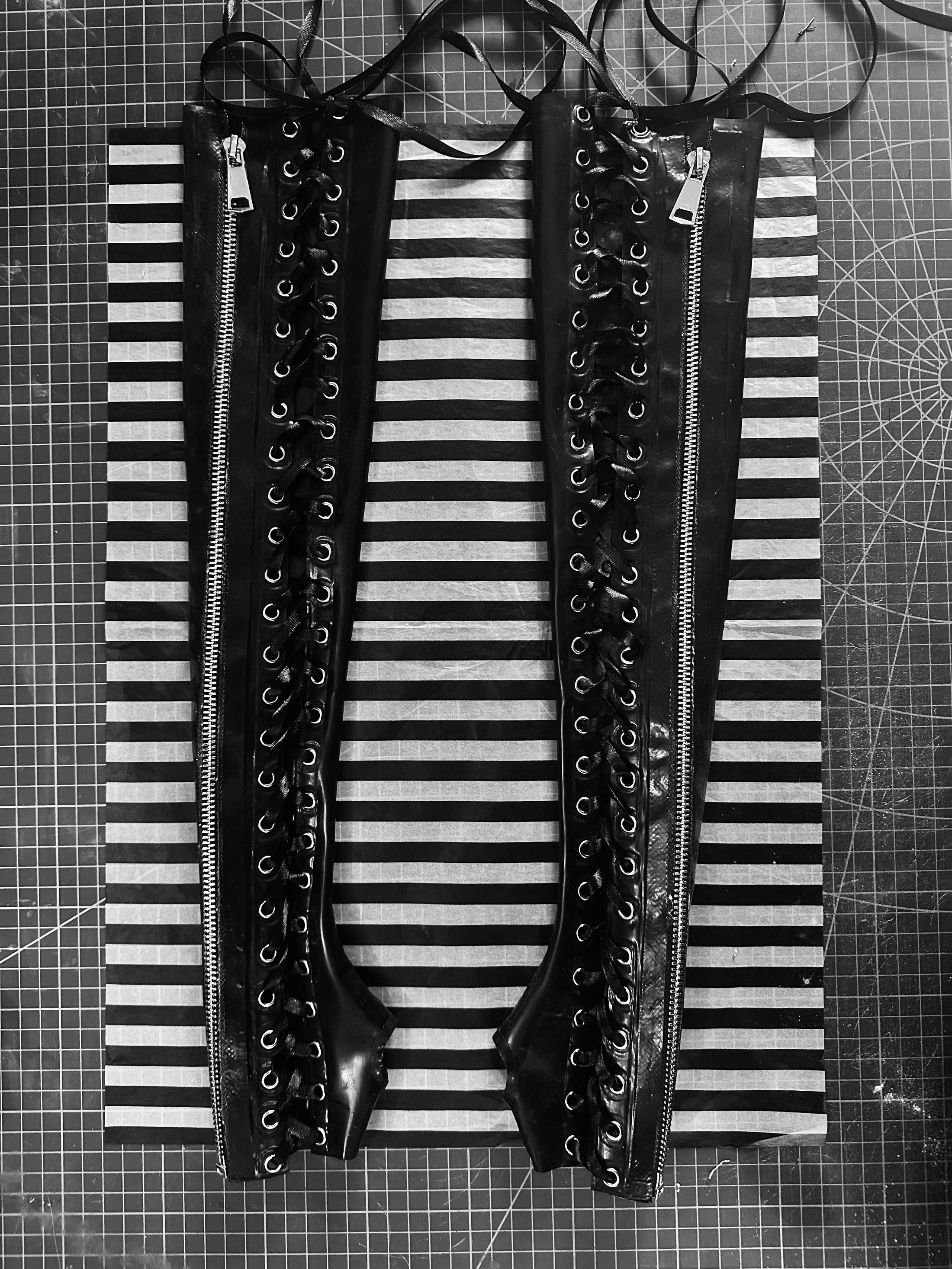 Close detail of the lace-up eyelets and metal zip on the latex gauntlets