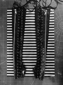 Close detail of the lace-up eyelets and metal zip on the latex gauntlets