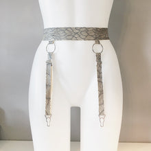 Close detail of the latex-lace texture and o-ring hardware on the suspender belt