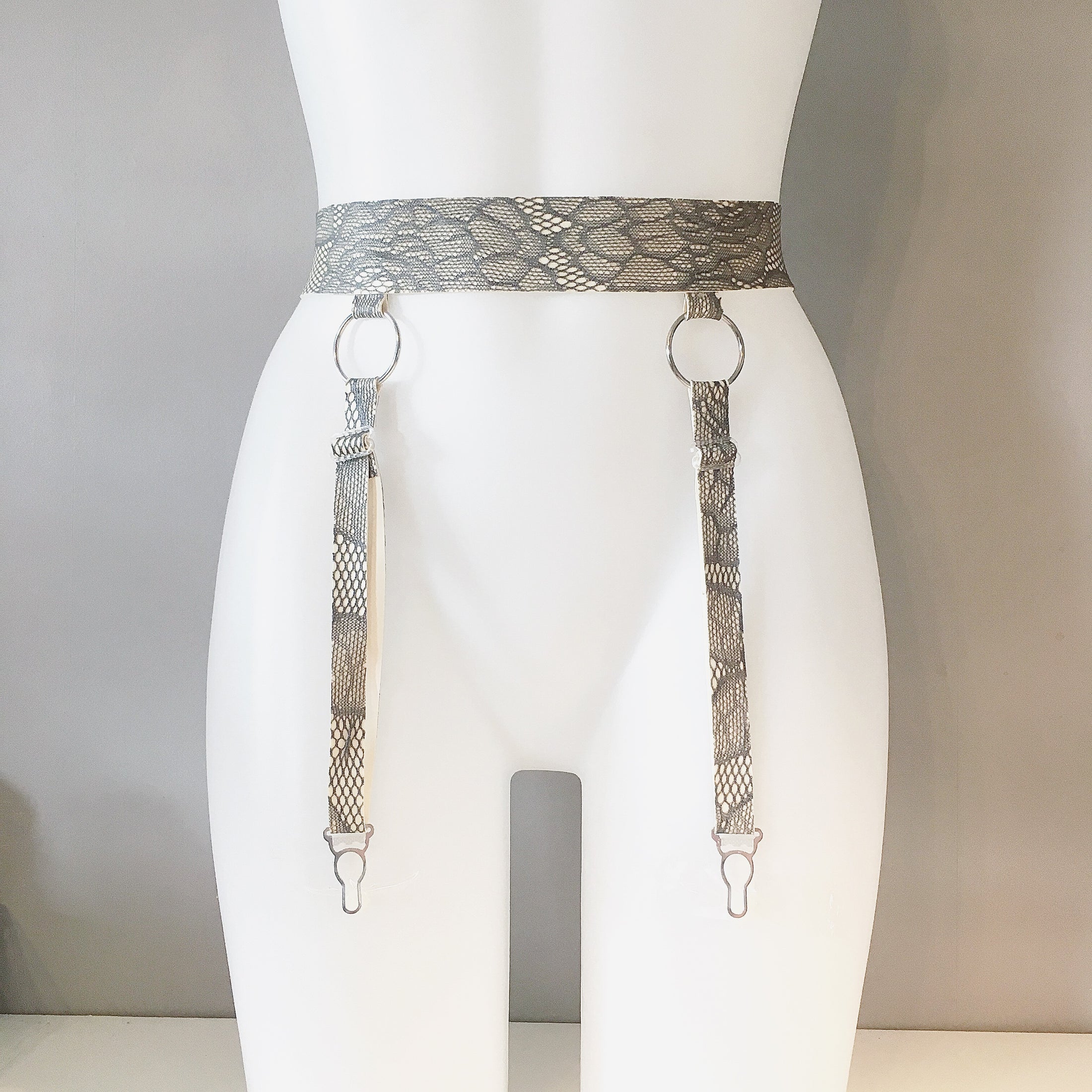 Close detail of the latex-lace texture and o-ring hardware on the suspender belt