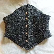 Close detail of the latex-lace texture and busk on the shaped corset