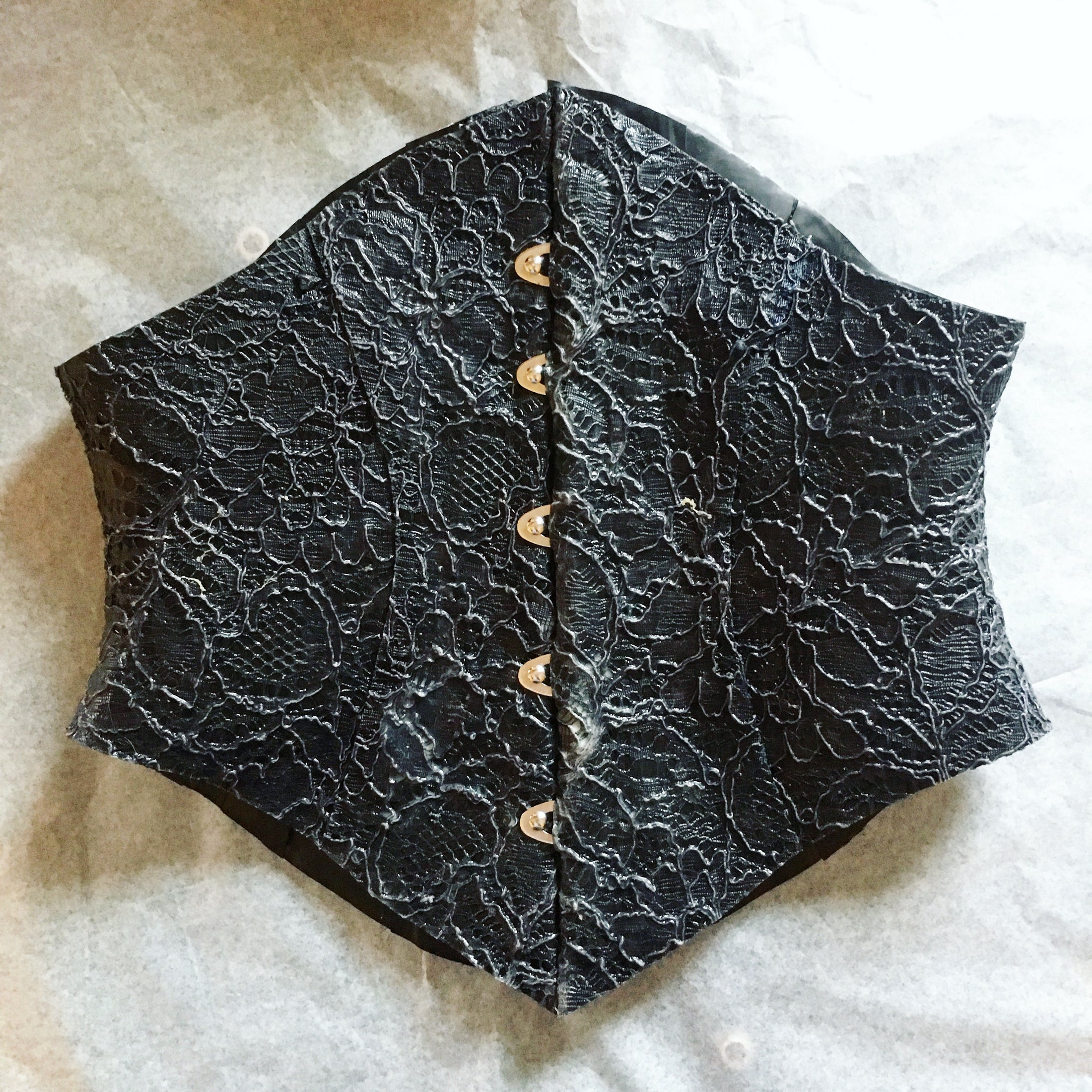 Close detail of the latex-lace texture and busk on the shaped corset