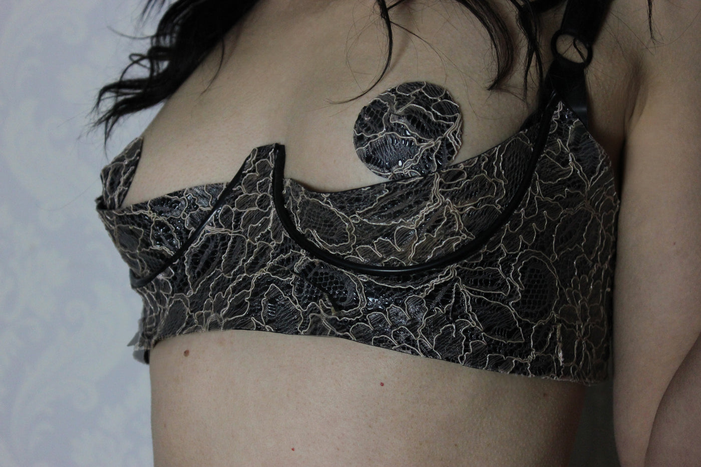Close detail of the adjustable straps and quarter cup shaping on the latex-lace bra