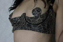 Close detail of the adjustable straps and quarter cup shaping on the latex-lace bra